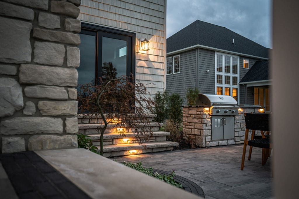 Custom stone steps with built-in grill and outdoor patio designed and installed by Ground Works