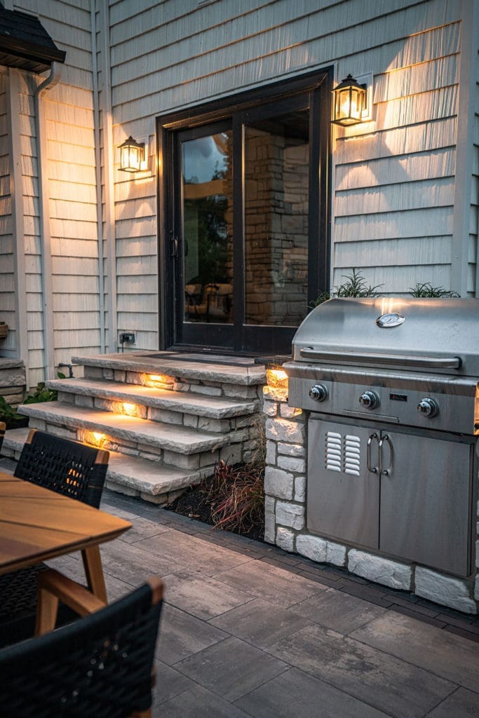 Custom stone steps with built-in grill and outdoor patio designed and installed by Ground Works